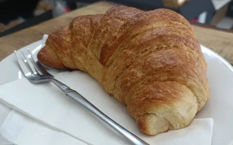 A flaky butter croissant on a plate at the bakery counter