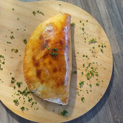 A golden folded calzone on a wooden board