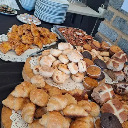 A catering spread of fresh pastries, rolls and muffins with urns