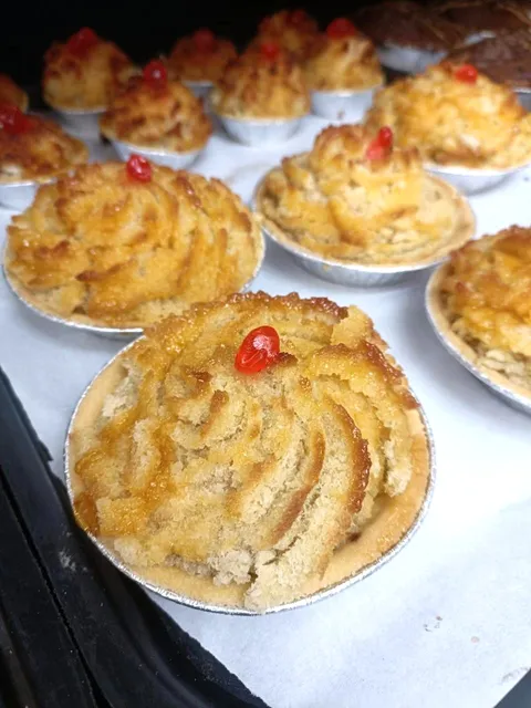 Baked coconut tarts topped with red glacé cherries