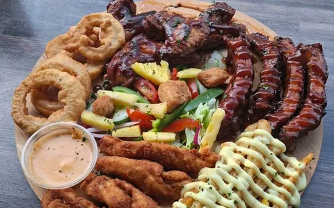 A sharing grill board with ribs, wings, chicken strips and onion rings